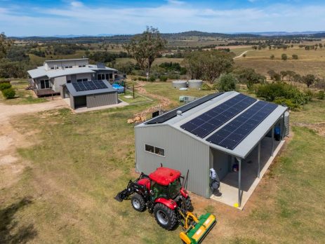 Rural Australian shed with rooftop solar panels overlooking open paddocks and native trees.
