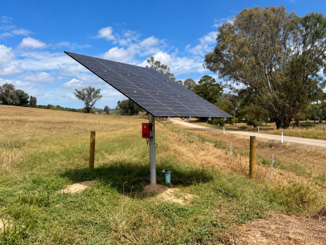Pole-mounted solar panels and pump controller beside a bore in an Australian farm paddock